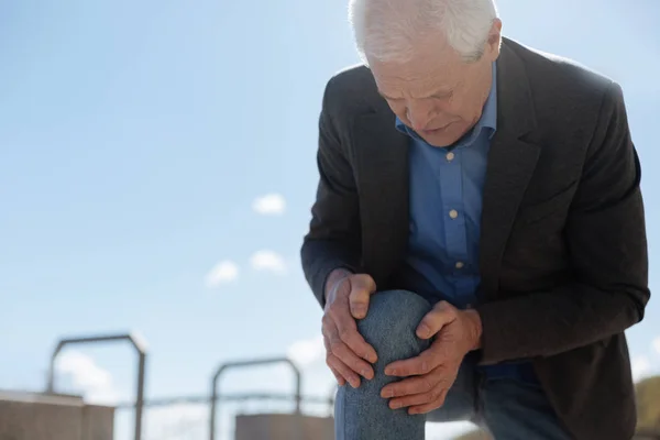 Plăcut pensionar devenind fără balamale din cauza durerilor de genunchi în parc — Fotografie, imagine de stoc