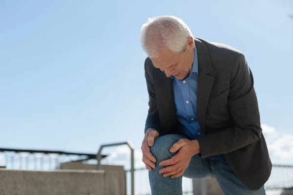 Retired man cutting up about his knee outdoors — Stock Photo, Image