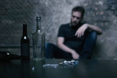 Alkol şişeleri ve kullanılan şırınga masanın üzerinde yatan