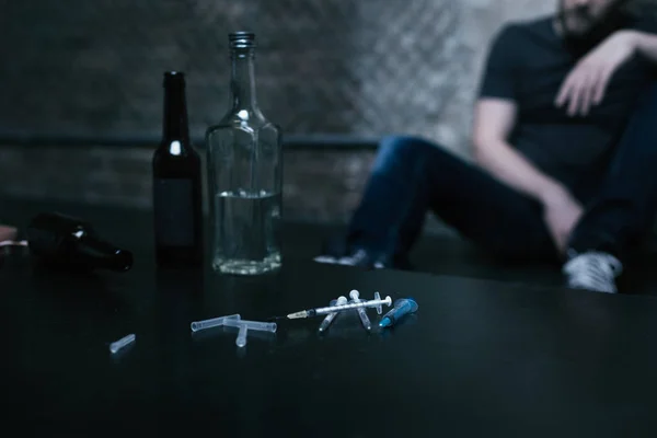 Flessen vol alcohol en spuiten liggen in de drug den — Stockfoto