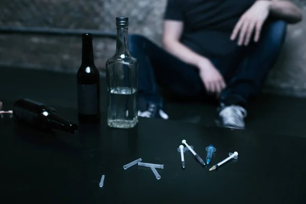 Diverses bouteilles et seringues couchées sur la table dans l'obscurité — Photo