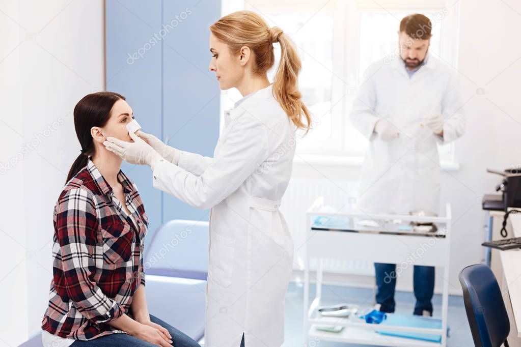 Experienced cosmetic surgeon looking at her patient