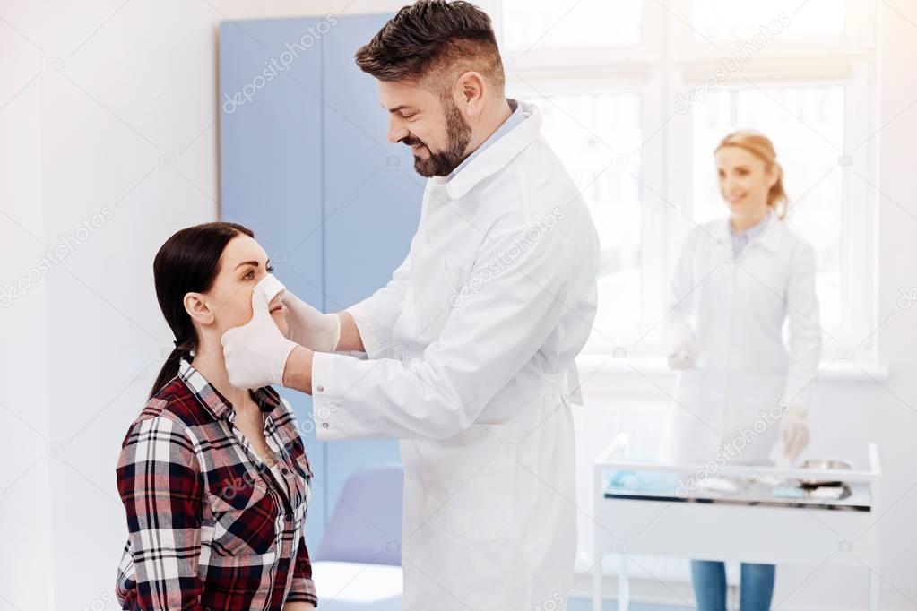 Positive friendly doctor standing in front of his patient