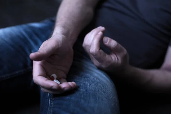 Reifer Junkie, der Heroin in Tablettenform in der Dunkelheit hält — Stockfoto