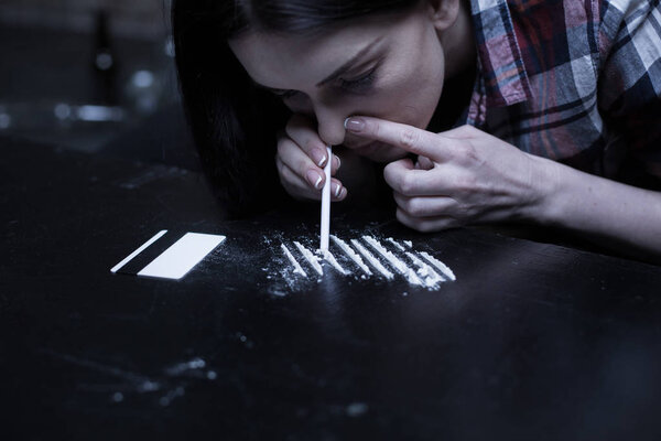 Drug addict snorting heroin lines in the dark place