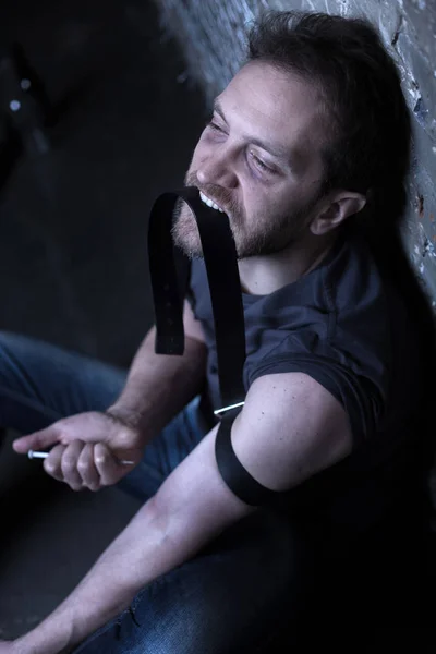 Őrült kábítószer felhasználó üzem fecskendő a sötét megvilágított szobában — Stock Fotó
