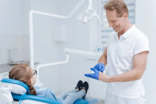 Buon dentista qualificato che indossa guanti speciali — Foto Stock