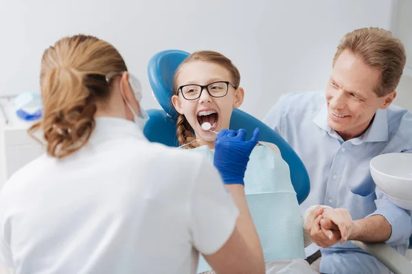 Adorável menina positiva visitando dentista com seu pai — Fotografia de Stock