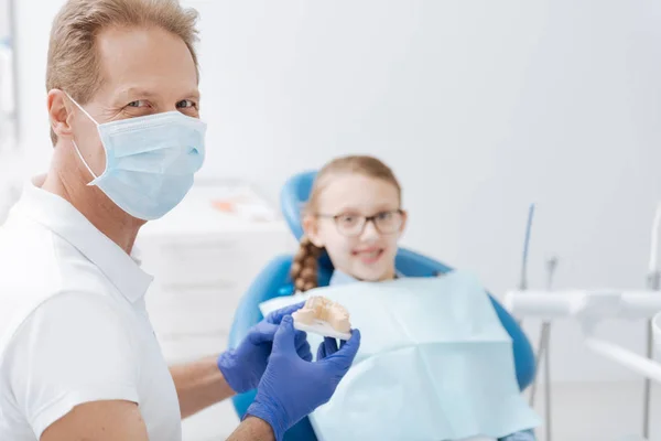Charming dentista competente ajudando seu pequeno paciente — Fotografia de Stock