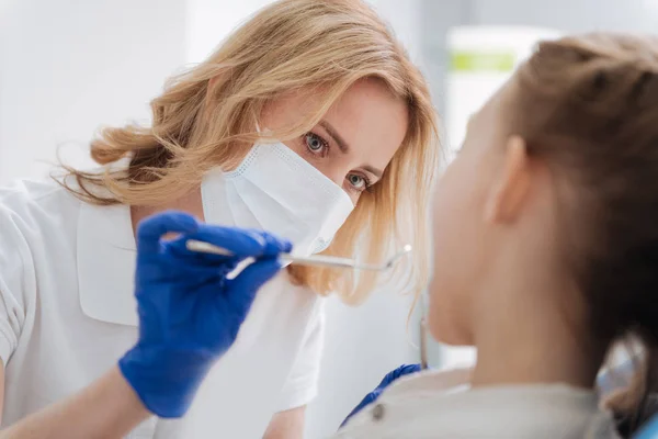 Mindful kvalificerad läkare noggrant undersöka tjejer tänder — Stockfoto