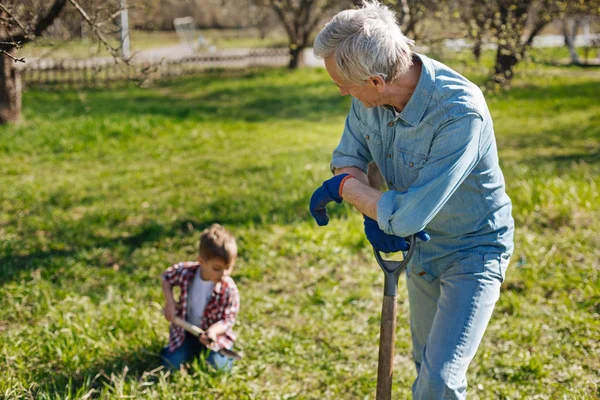 Man kijken van zijn kleinzoon graven in de bodem — Stockfoto