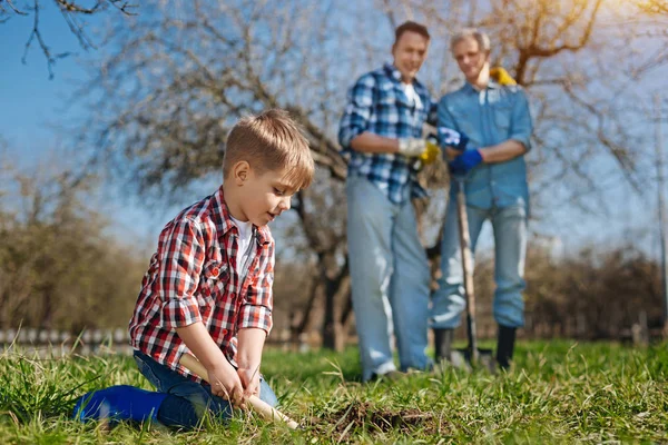 Idősebb nemzedék néz aranyos gyermek scooping föld — Stock Fotó
