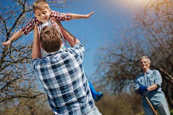 Vader zoon overhead in tuintje te houden — Stockfoto