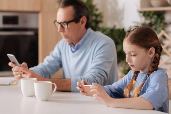 Hombre y niña utilizando teléfonos innovadores — Foto de Stock