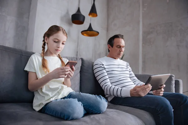 Petite-fille et grand-père sans émotion jouant à des jeux numériques à la maison — Photo