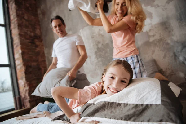 Menina divertida tendo travesseiro luta com os pais em casa — Fotografia de Stock