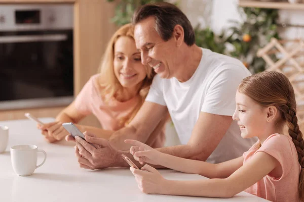 Alegre padres e hija usando aparatos electrónicos en interiores — Foto de Stock