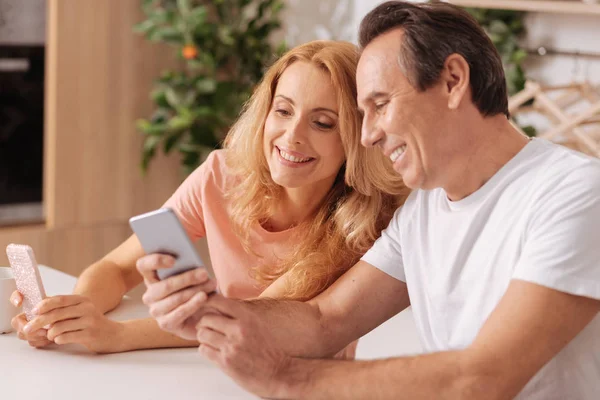 집에서 디지털 스마트폰을 사용 하 여 긍정적인 성숙한 부부 — 스톡 사진
