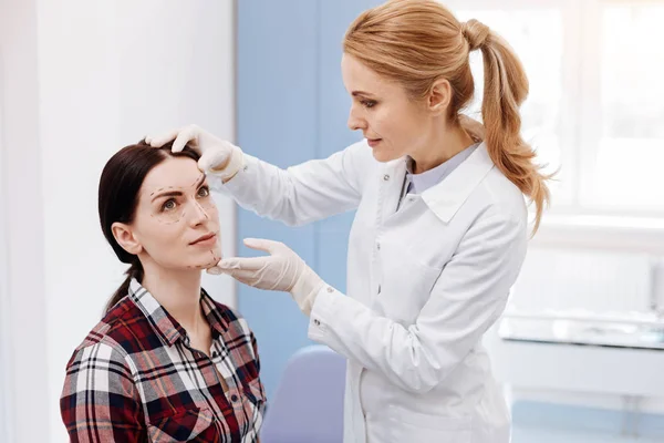 Female plastic surgeon looking at her patients face — Stock Photo, Image