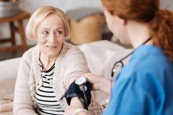 Calmo senhora idosa ter sua pressão arterial verificada — Fotografia de Stock