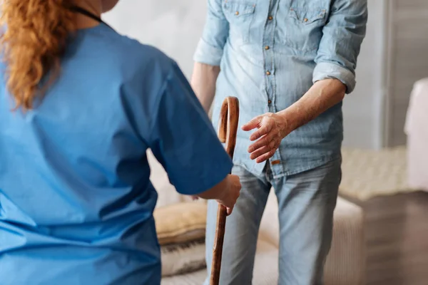 Committed kind medical worker giving her patient a cane — Stock Photo, Image