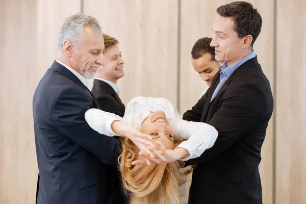 Feliz hermosa mujer siendo retenida por sus colegas — Foto de Stock