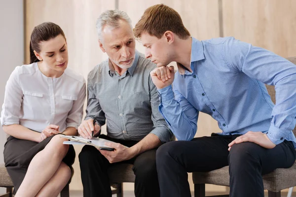 Guapo hombre considerado sentado con sus colegas — Foto de Stock