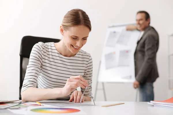 Vrolijke vrouwelijke ingenieur tekenen met kompassen — Stockfoto