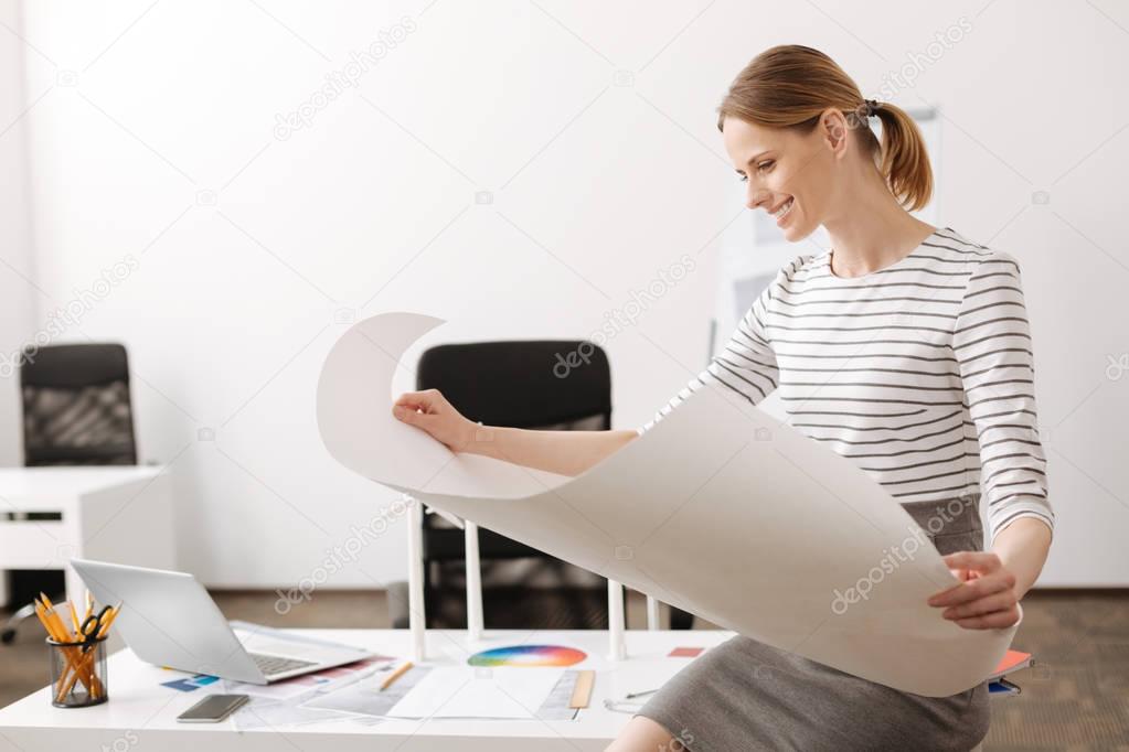 Cheerful female engineer holding a blueprint