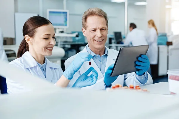 Positiv entzücktes Wissenschaftlerehepaar beim Blick auf Bildschirm des Tablets — Stockfoto