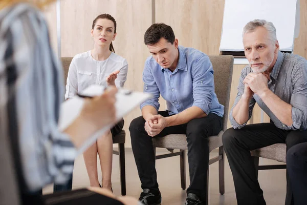 Ernsthafte erwachsene Menschen auf den Stühlen — Stockfoto