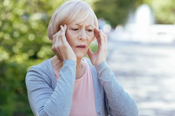 Worried pensioner having headache outdoors — Stock Photo, Image