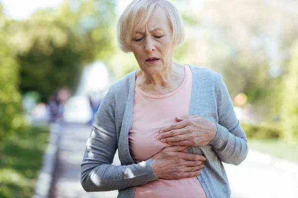 Mujer envejecida desconcertada teniendo un ataque al corazón al aire libre — Foto de Stock