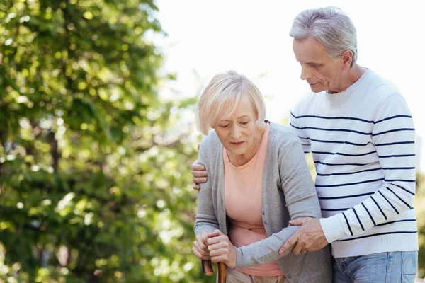 Hombre envejecido atento que apoya a la esposa mayor al aire libre —  Fotos de Stock