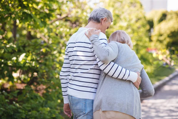 Helpful man helping senior wife in the park — Stock Photo, Image