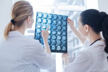 Optimistic neurologists analyzing x ray photo at the roentgen cabinet clipart