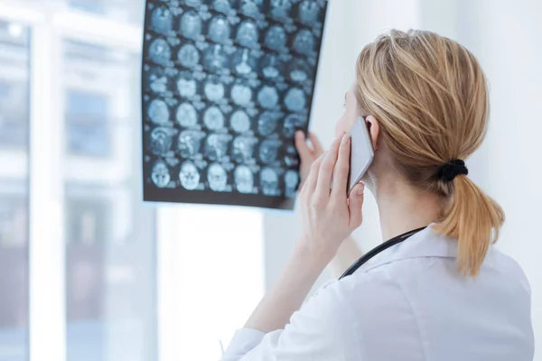 Médico hábil discutiendo rayos X cerebrales en la clínica — Foto de Stock