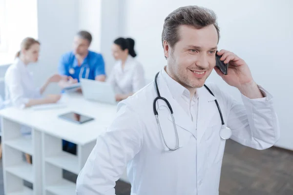 Medico allegro utilizzando smartphone al lavoro — Foto Stock