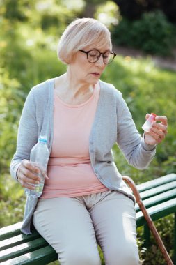 Şişe hap ile açık havada tutan konsantre yaşlanma kadın