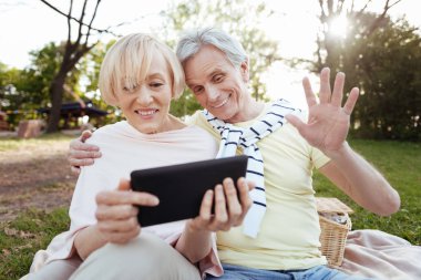 Parkta tablet kullanarak iyimser yaşlı çift