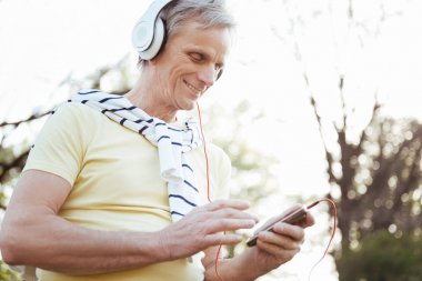 Gülümseyen yaşlı adam açık havada elektronik araçları kullanma