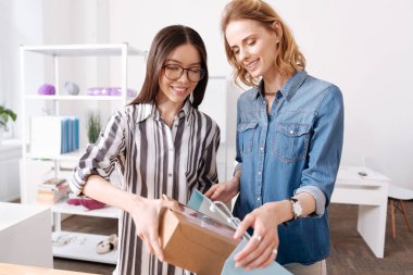 Bir kutu torbaya koyarak iki gülümseyen kadın