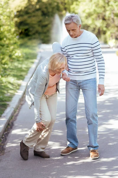 Внимательный пенсионер помогает старшей жене на улице — стоковое фото