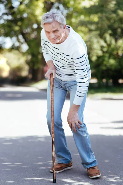 Confused pensioner feeling ache in knee outdoors — Stock Photo, Image
