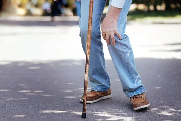 Ill aged man touching ill knee outdoors — Stock Photo, Image