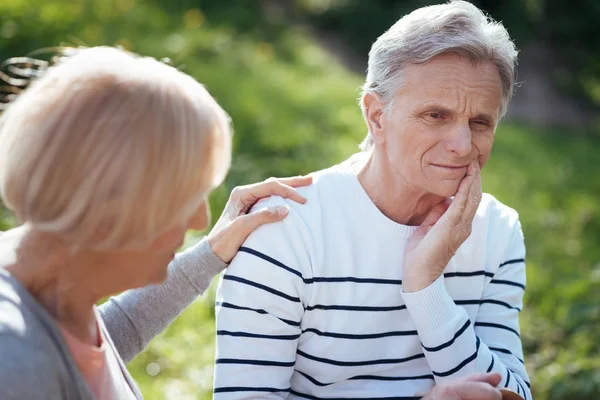 Depressed pensioner having toothache outdoors