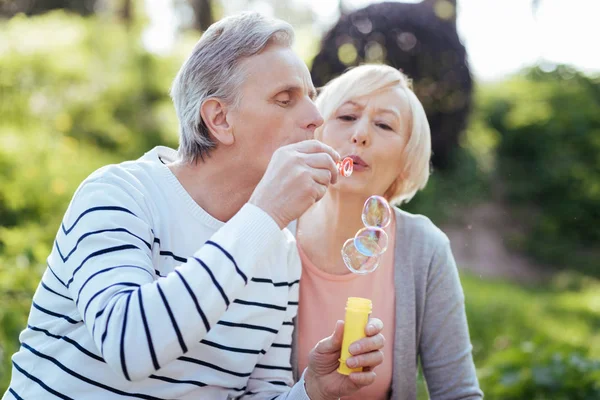 Blij gepensioneerden zeepbellen maken in het park — Stockfoto