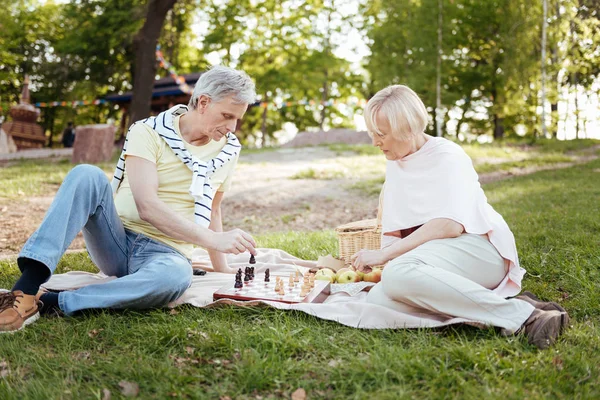 Calma pareja envejecida jugando al ajedrez en el picnic —  Fotos de Stock