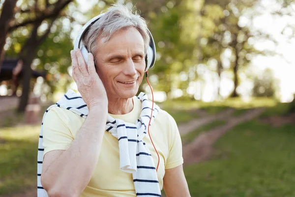 Inspired aging man enjoying music outdoors — Stock Photo, Image