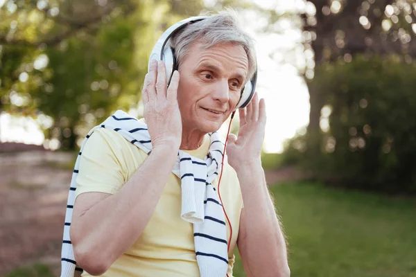 Härlig senior mannen njuter av musik i hörlurar utomhus — Stockfoto